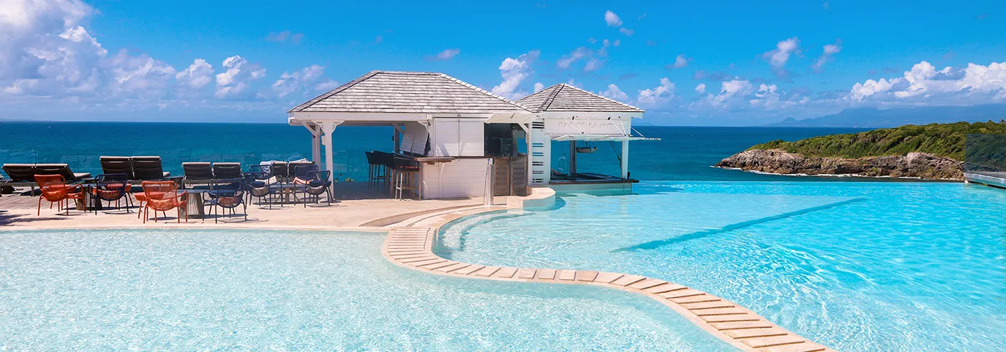 Large turquoise pool with bar and seaside terrace in Guadeloupe | Woman in a bathrobe relaxing with a snack and a drink in a spa area