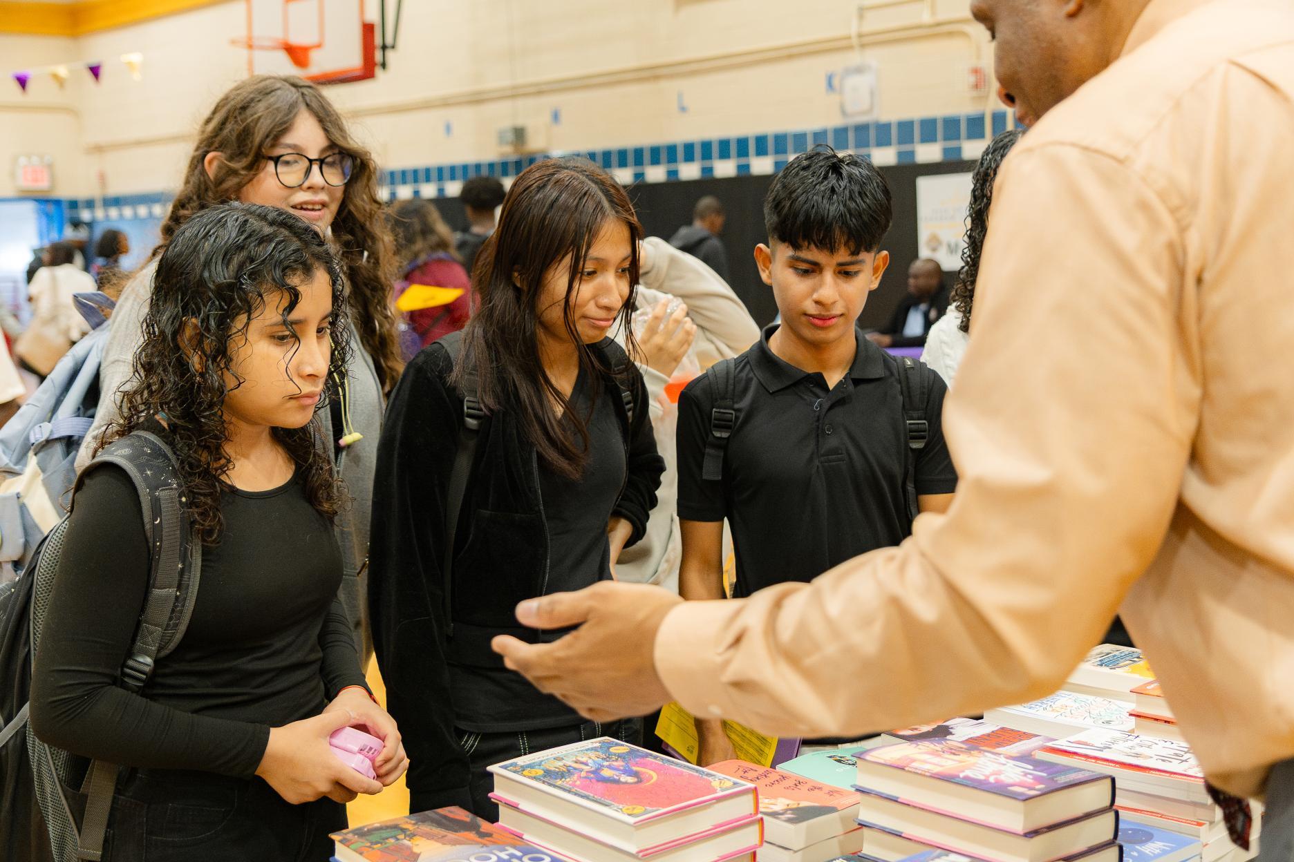 Students browsing books at a school book fair in gymnasium
