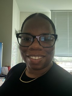 Shakell Mitchell smiling staff member wearing glasses and gold necklace