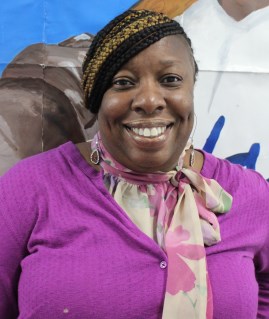 Gloria Chambers smiling in a purple cardigan and floral scarf