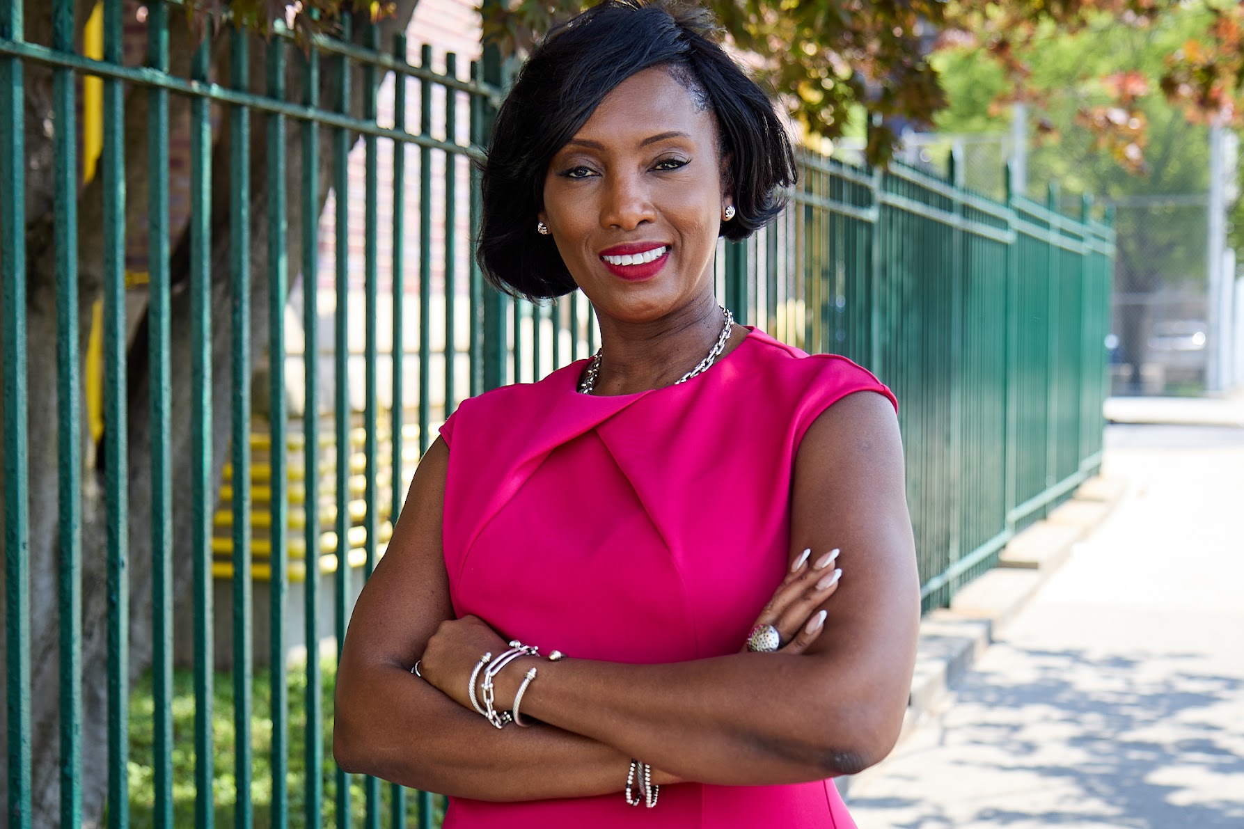 Principal smiling outdoors in front of school fence