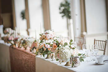 Elegant event venue table set with floral centerpieces, glassware, and china in a bright Dallas Fort Worth banquet hall.