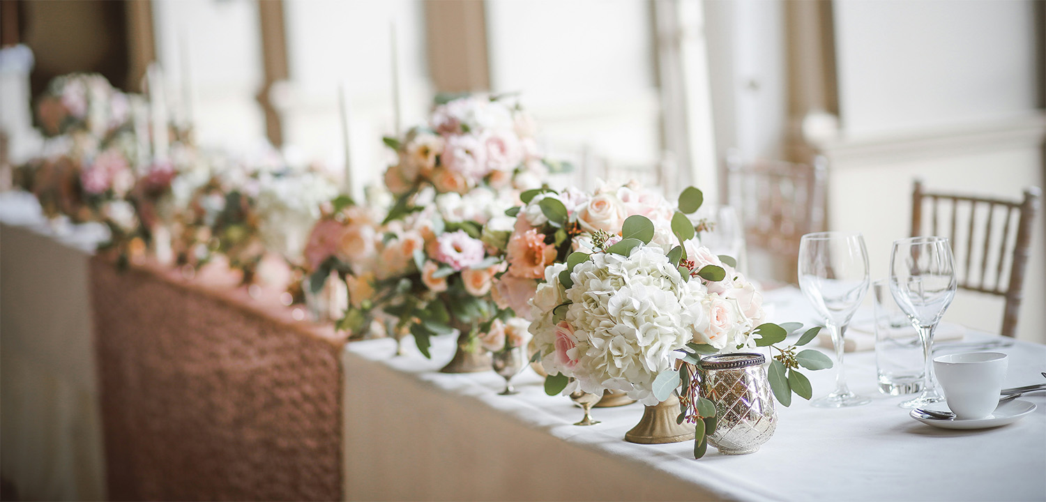 Elegant event venue table set with floral centerpieces, glassware, and china in a bright Dallas Fort Worth banquet hall.