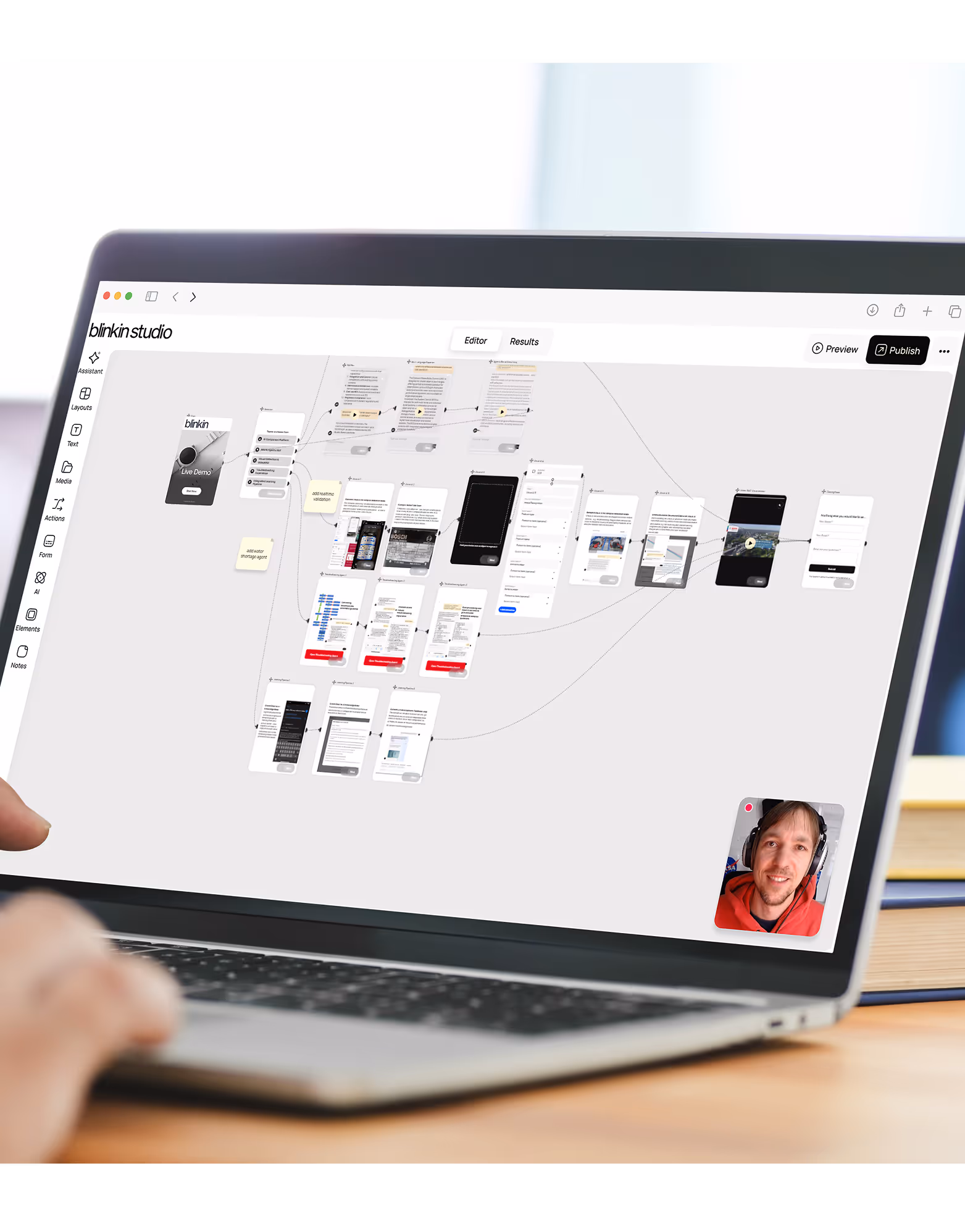 Laptop screen showing a Blink Studio interface with a flowchart or wireframe design and a video call thumbnail of a man wearing headphones and a red hoodie.