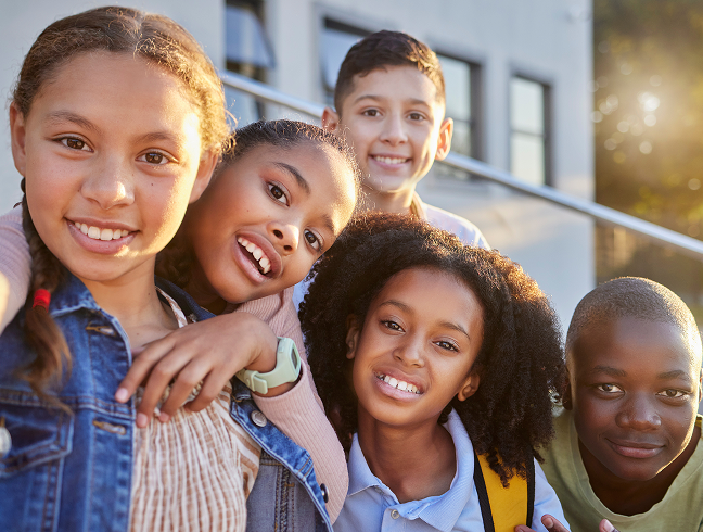 Group of five happy children smiling and looking down at the camera in a circle.