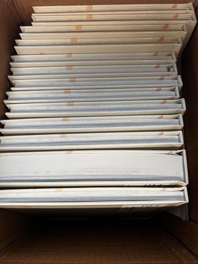 Box of yearbooks with one extra thick book because the parent who purchased added 100 custom pages to celebrate her child.