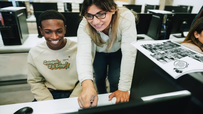 Yearbook teachers helps a student make a yearbook online