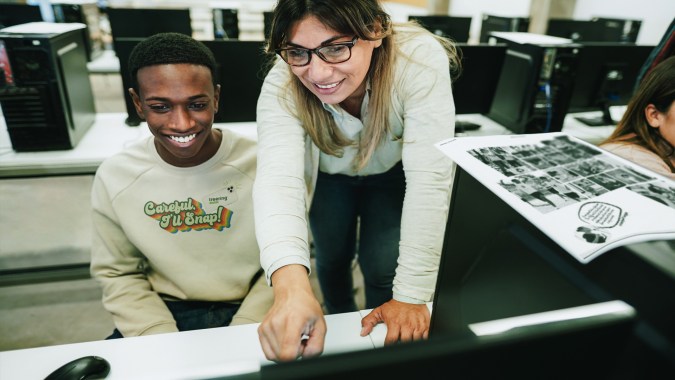 Yearbook teachers helps a student make a yearbook online