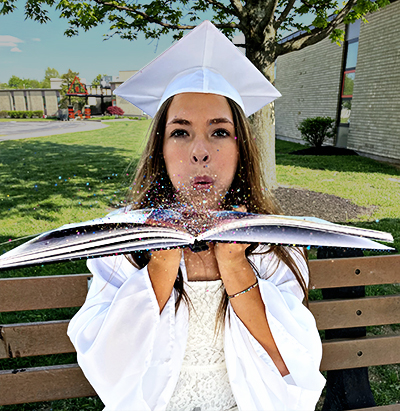 Female senior blowing glitter from the margin of her yearbook