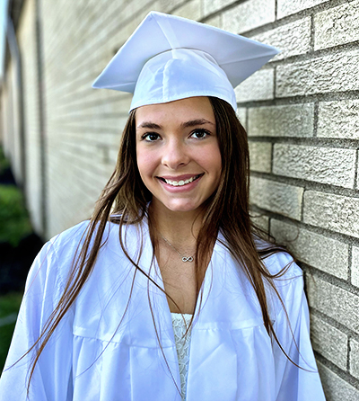 Graduation photo of a senior against a brick wall