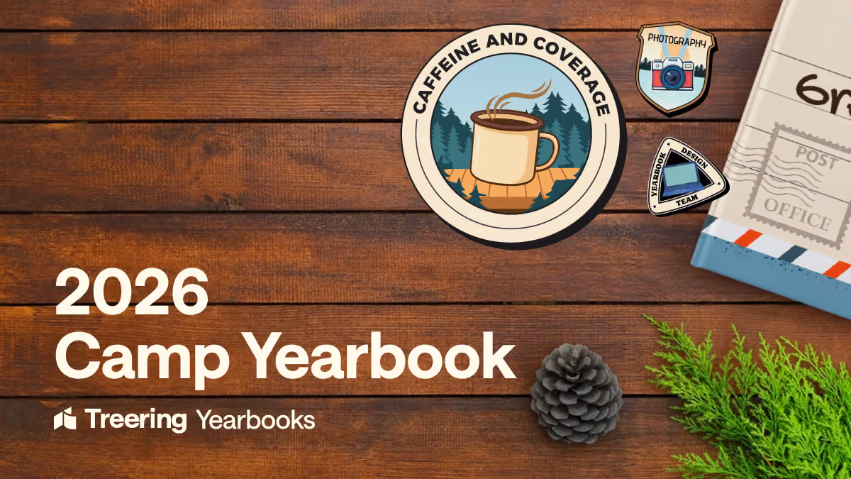 Wooden table with 2026 Camp Yearbook text, patches, pinecone, greenery, and a book corner.