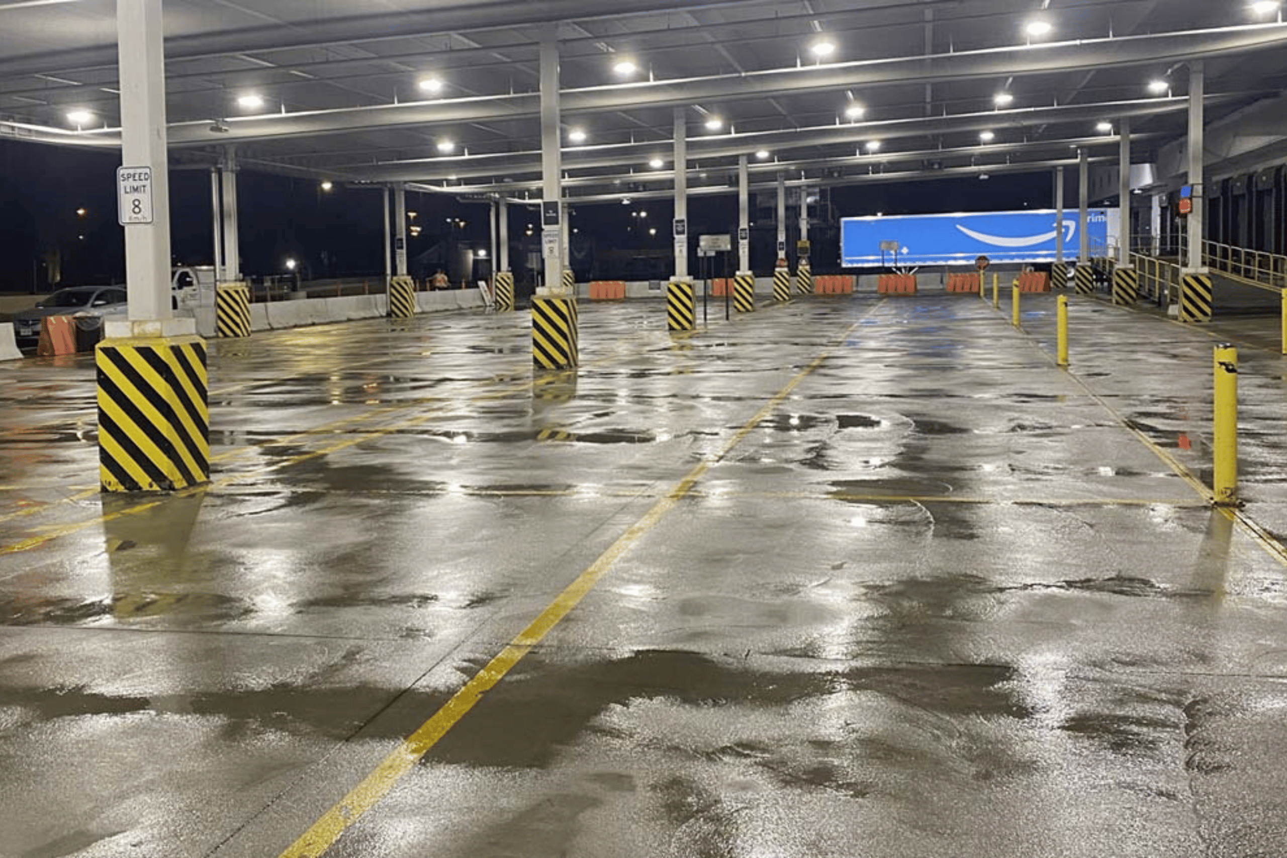 A parking lot with a blue Amazon truck parked in it.