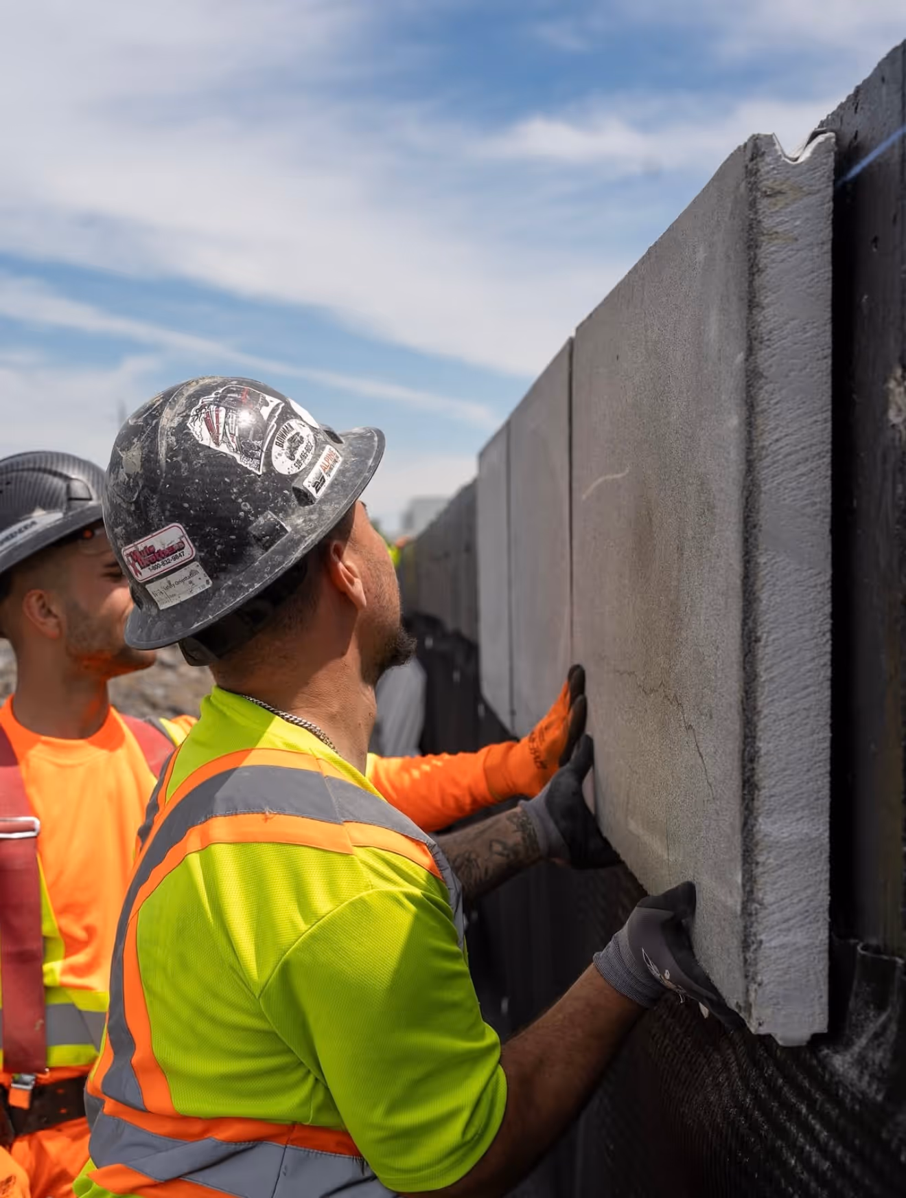 Two men working on a concrete wall.