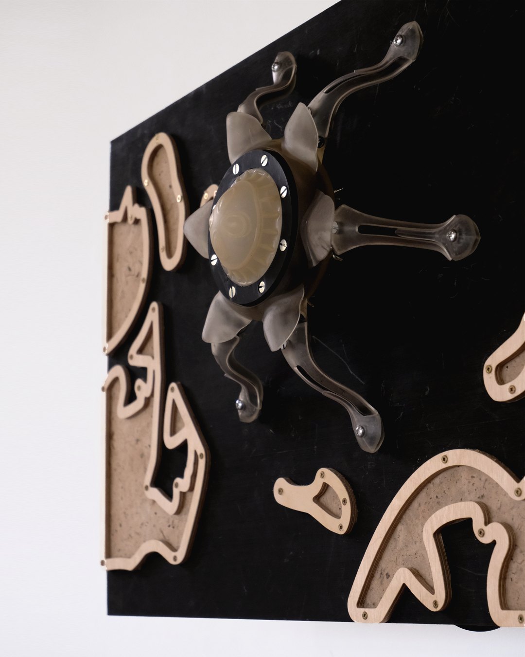 Wall piece of laser-cut wooden shapes and a central hub on black