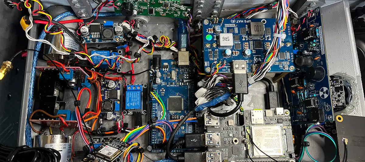 Unutrašnjost elektronskog uređaja sa raznobojnim žicama i pločicama sa komponentama.