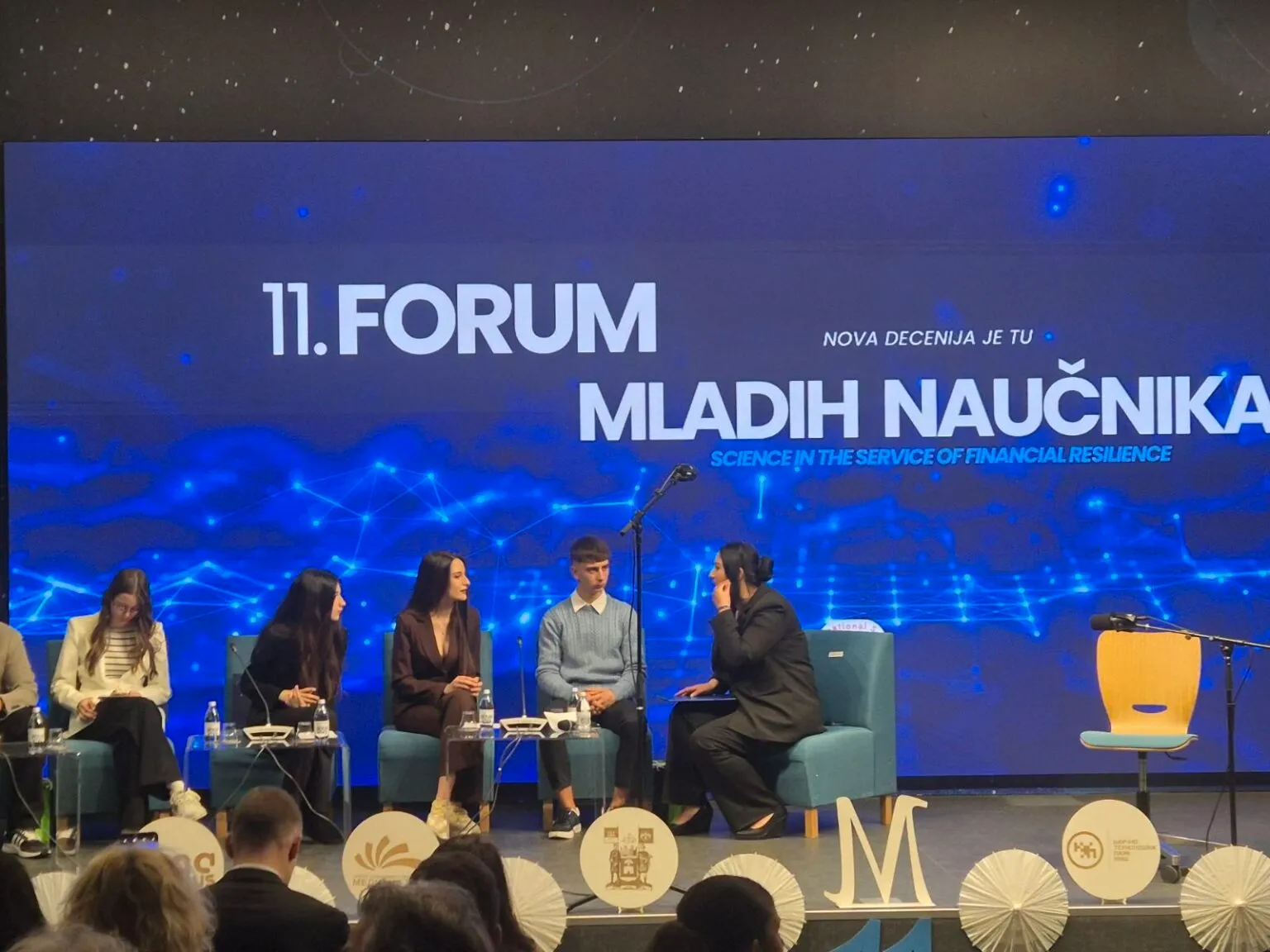 Mladi naučnici sede na bini tokom 11. Foruma mladih naučnika o finansijskoj otpornosti.