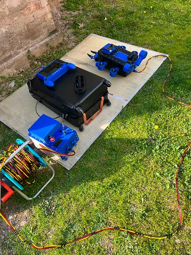Plavi robotski uređaji i oprema za daljinsko upravljanje raspoređeni na dasci na travnatom terenu.