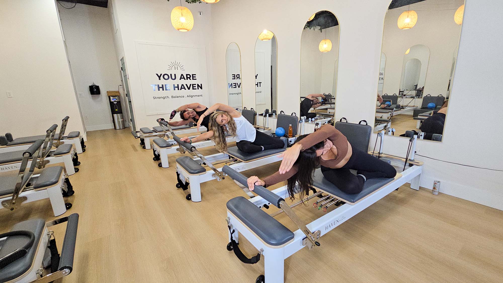 A few women in a Pilates class holding their hands over their heads