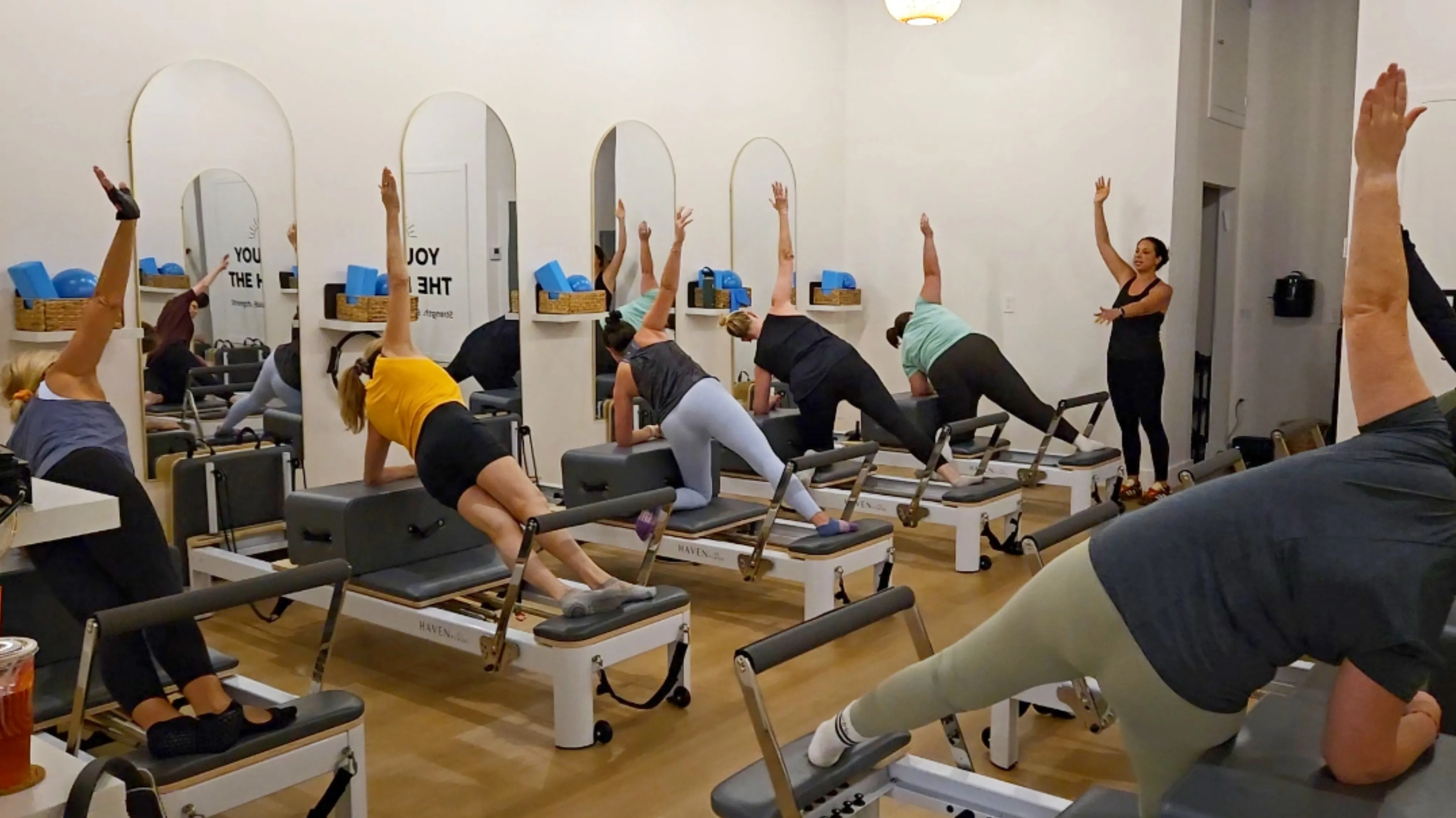Clients doing a plank on the reformer during a Pilates class at Haven Pilates Boca Raton