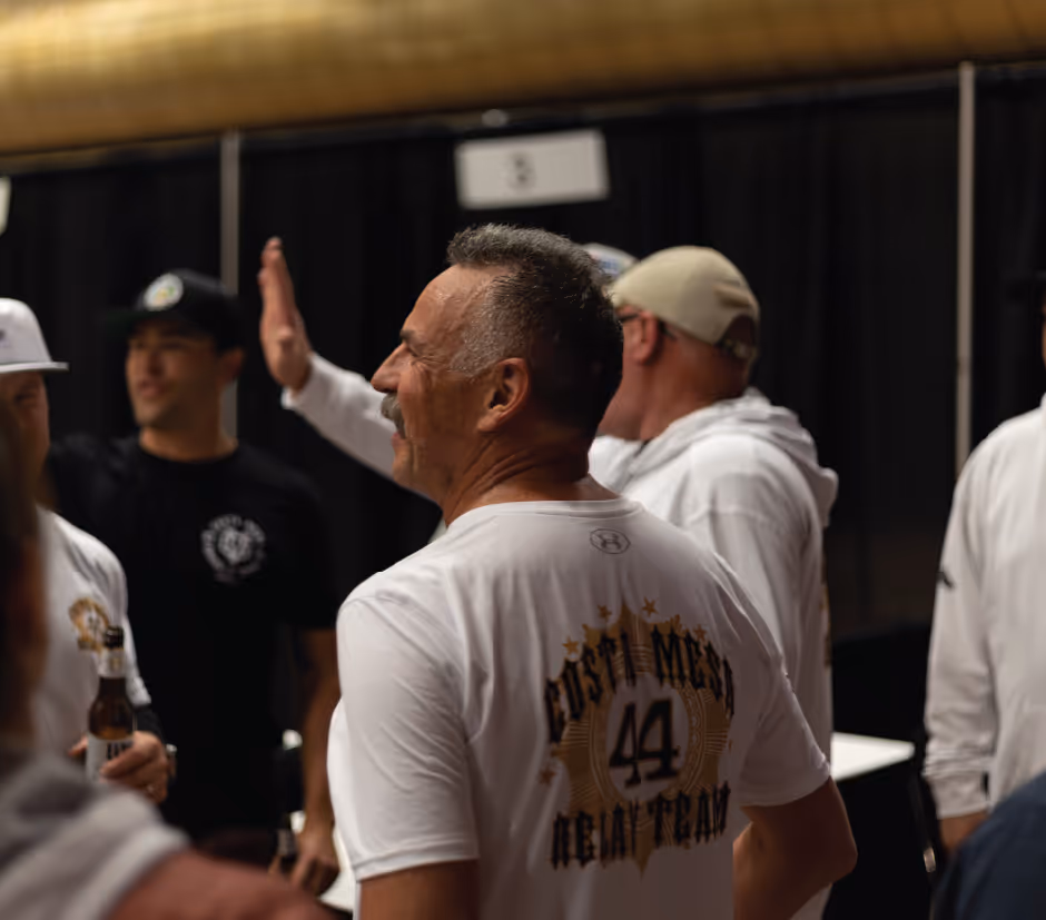 Costa Mesa relay team members gathered indoors, wearing matching shirts and celebrating
