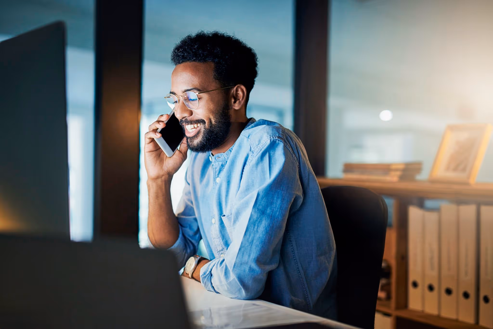 A wealth planner speaking on the phone while reviewing their client's portfolio on their computer.