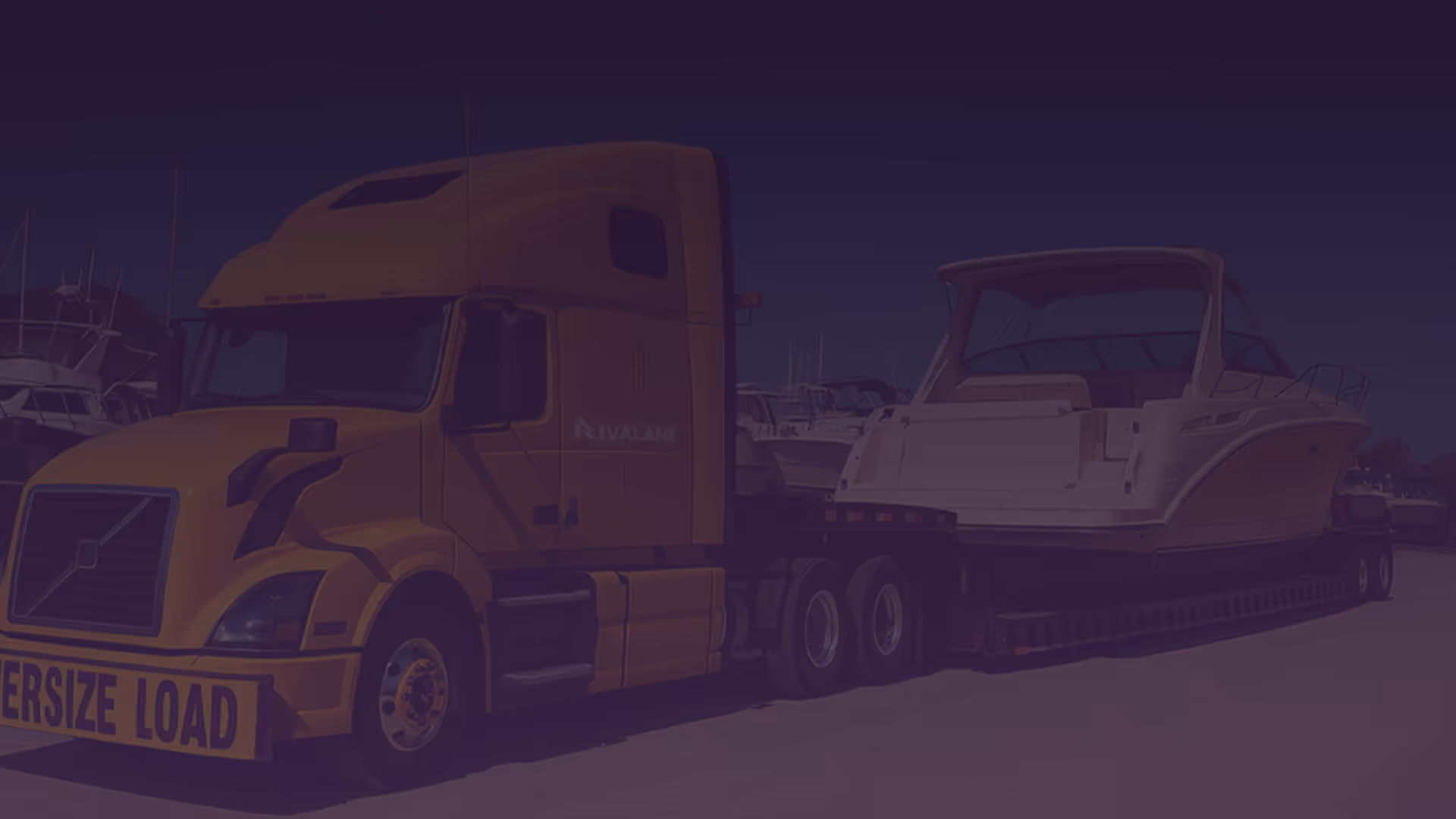 Yellow truck transporting a white yacht on a trailer with an Oversize Load sign.