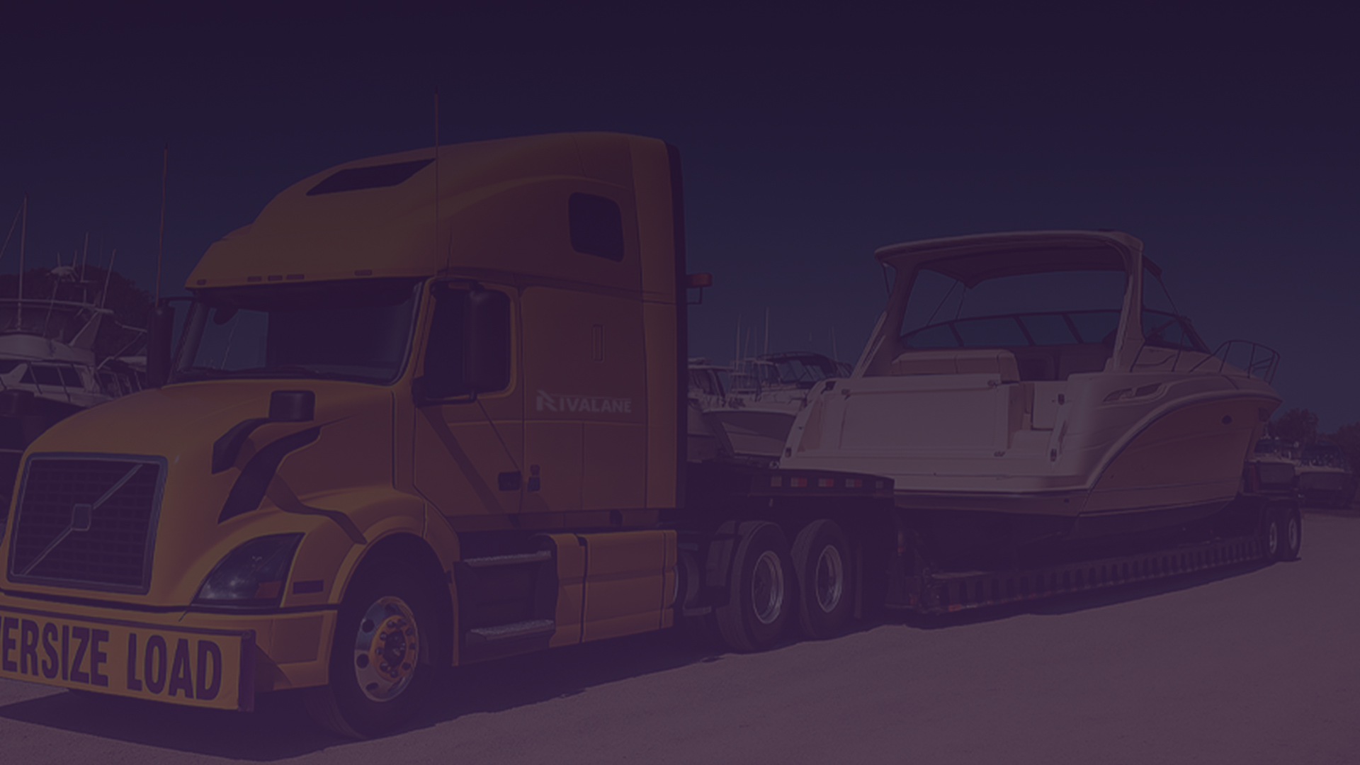 Yellow truck transporting a white yacht on a trailer with an Oversize Load sign.