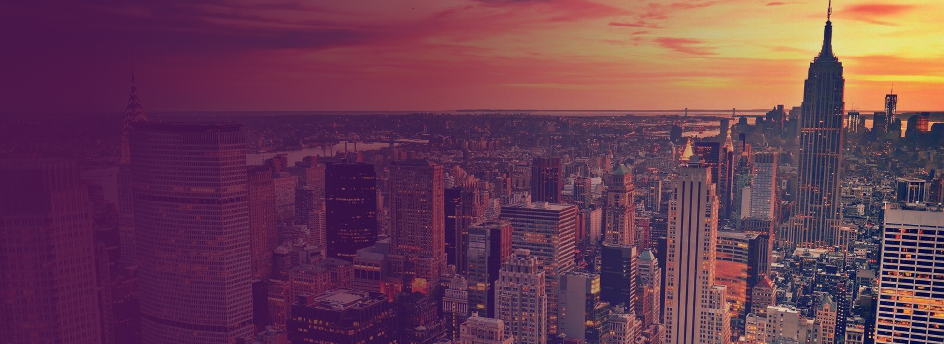 View of New York City skyline at sunset with the Empire State Building prominently visible.