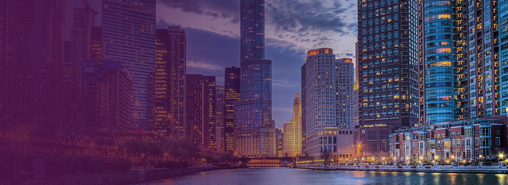 Evening view of Chicago skyline with illuminated skyscrapers reflecting on the Chicago River.