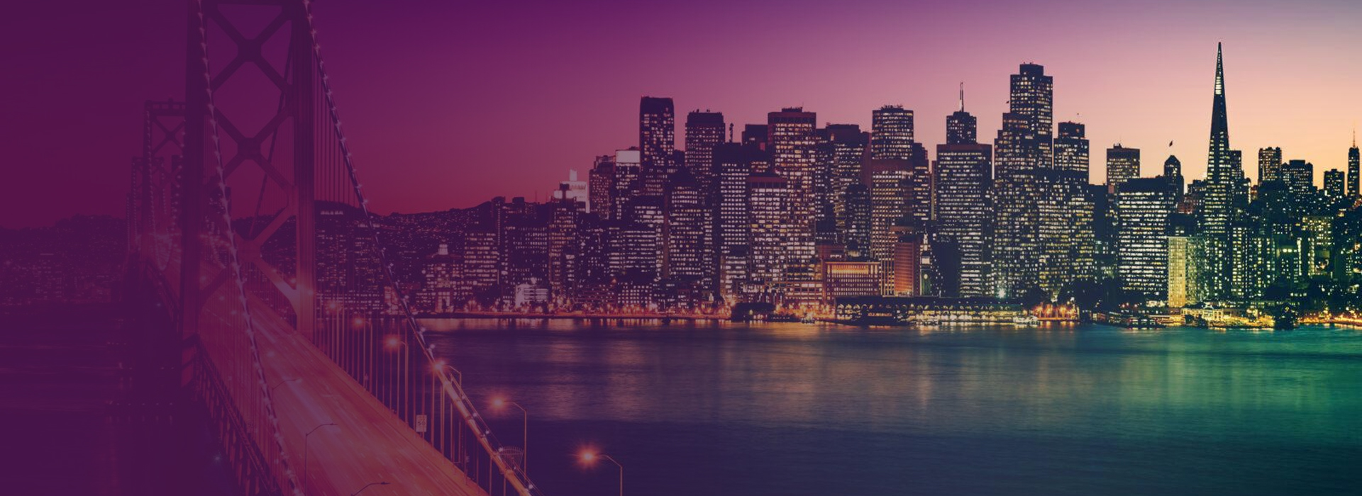 San Francisco skyline at dusk with the illuminated Bay Bridge on the left and city lights reflecting on the water.