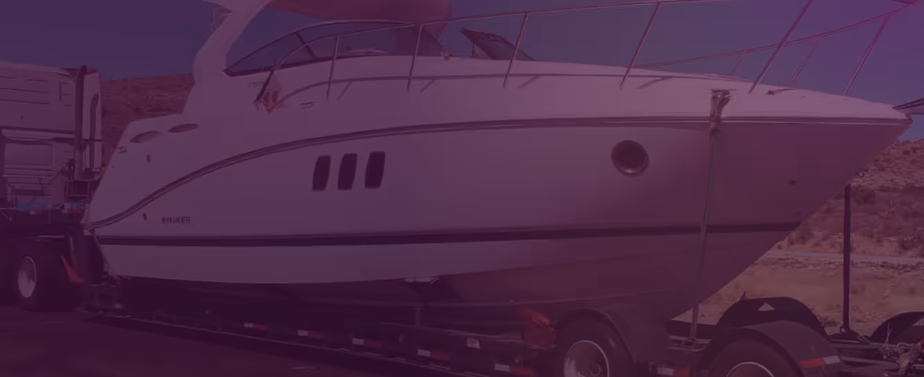 White yacht secured on a trailer attached to a truck, with a desert landscape in the background.