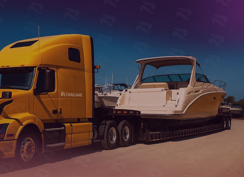 Yellow semi-truck transporting a large white yacht on a flatbed trailer in a sunny outdoor setting.