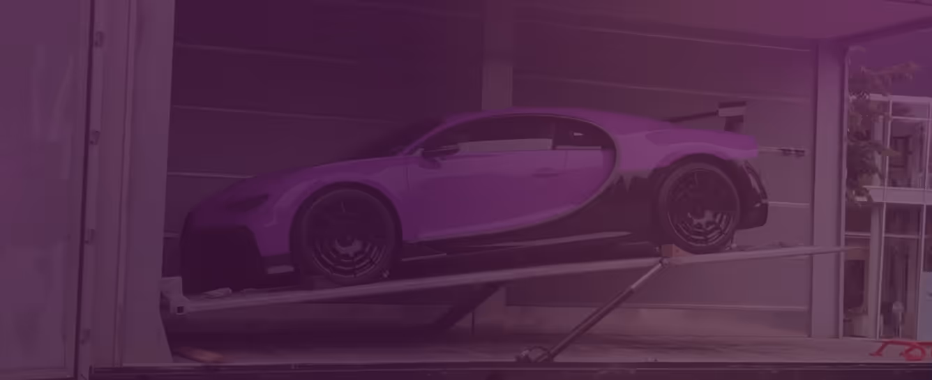 Bugatti sports car elevated on a hydraulic platform inside a shipping container.