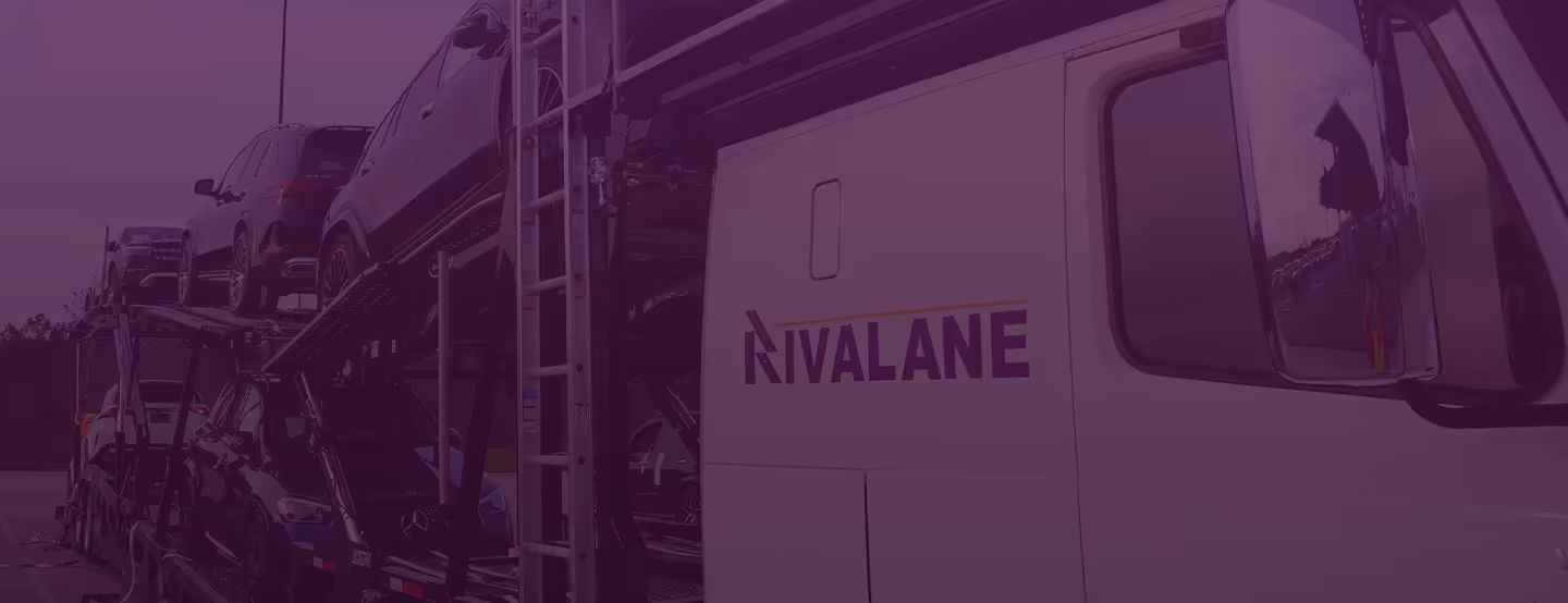 Car carrier truck loaded with multiple vehicles parked outdoors near trees.