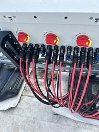 The image shows a panel with multiple red and black wires, some of which are connected to switches, indicating a control system, possibly for an electrical or mechanical device.AI-generated content may be incorrect.