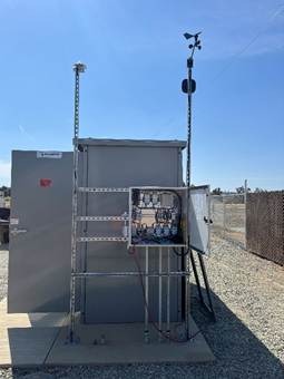 The image shows a solar power station with a large metallic structure, solar panels, and various electrical equipment, all situated against a clear blue sky and a chain-link fence.AI-generated content may be incorrect.