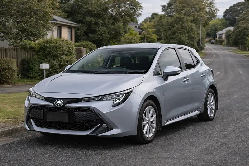 Side view of a red hatchback car with black wheels and sporty design details.