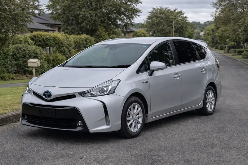 Silver Toyota Prius parked on a suburban street with greenery in the background.