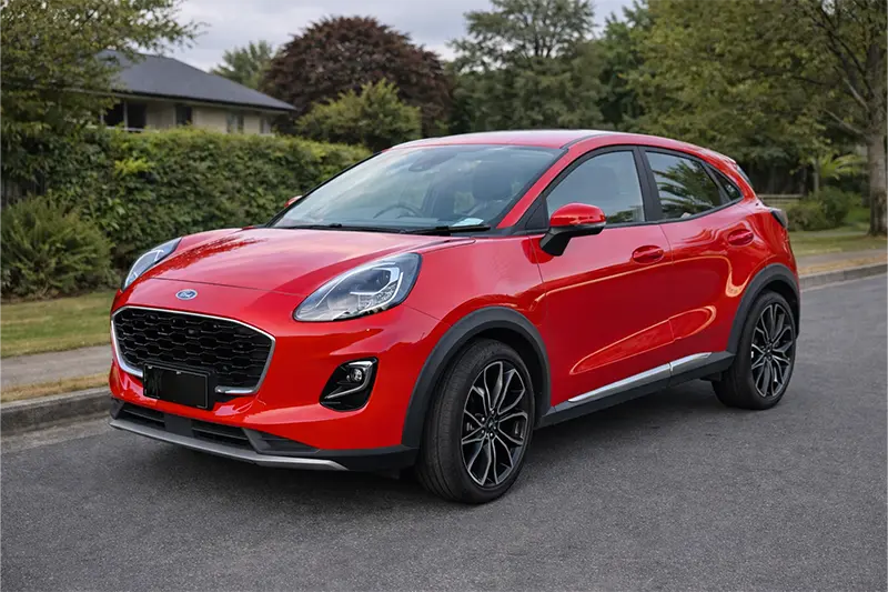 White Toyota Hilux pickup truck parked on a road near greenery and trees.