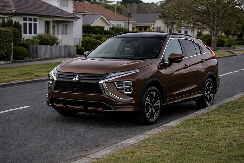 White Toyota Hilux pickup truck parked on a road near greenery and trees.