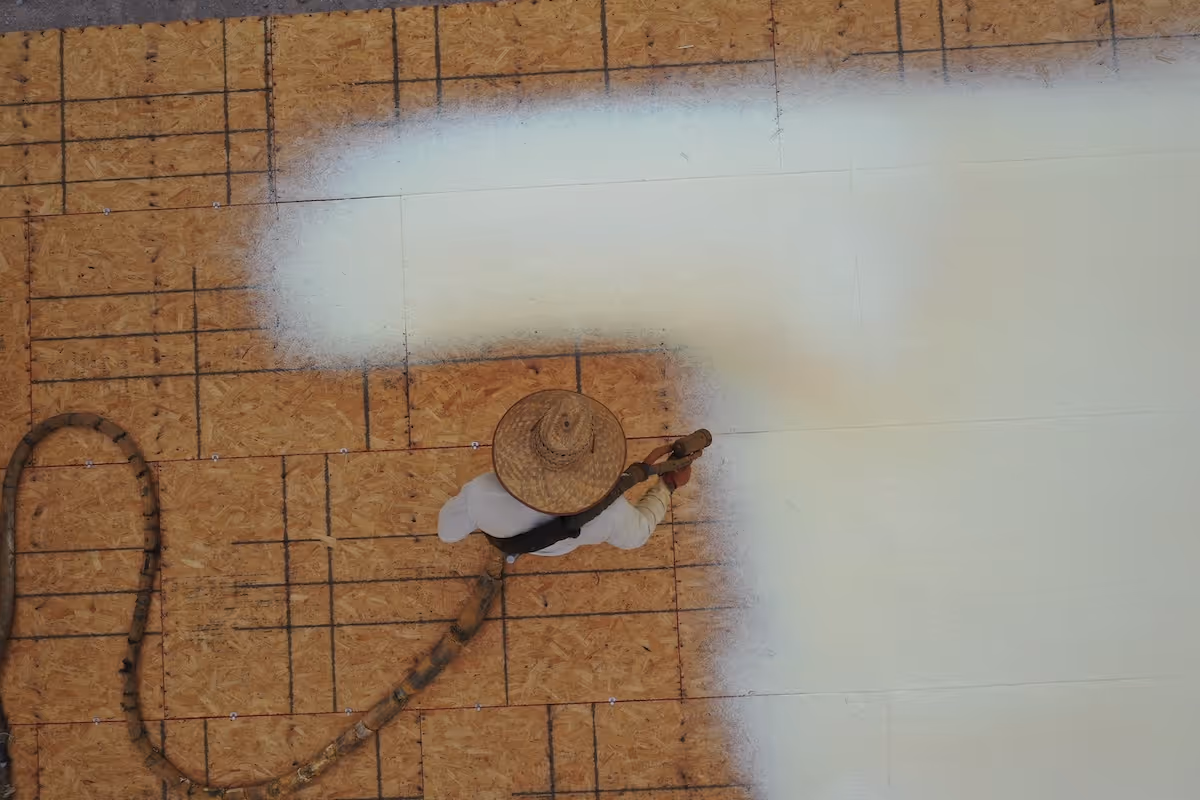 A roofer installing Polyurethane Spray Foam to a roof deck