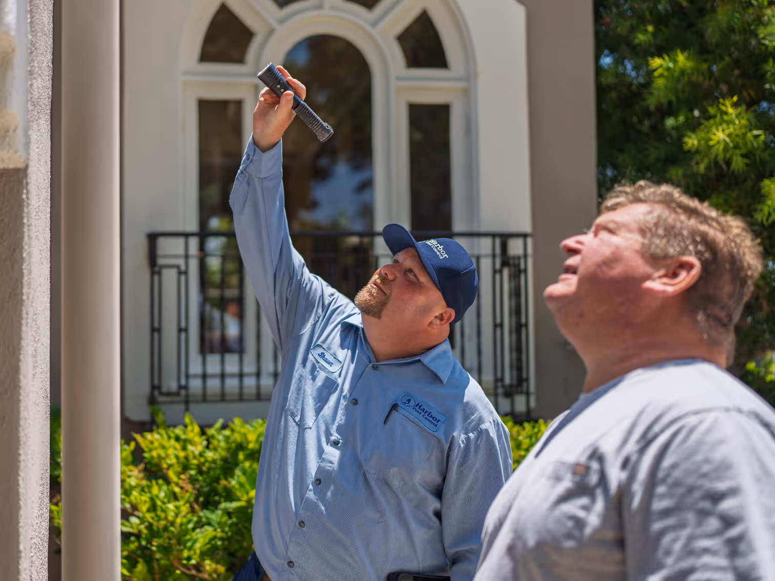 harbor pest control tech and homeowner looking at wasp nest 