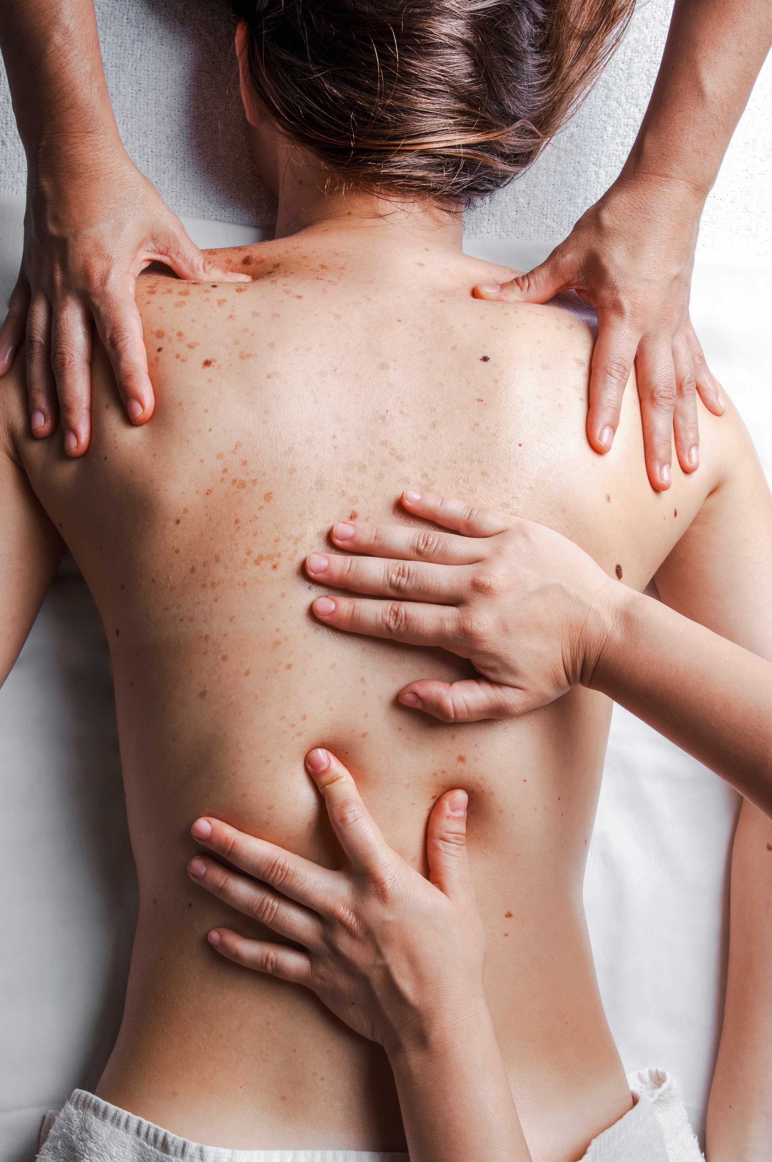 A woman with four hands on her back, giving her a massage.