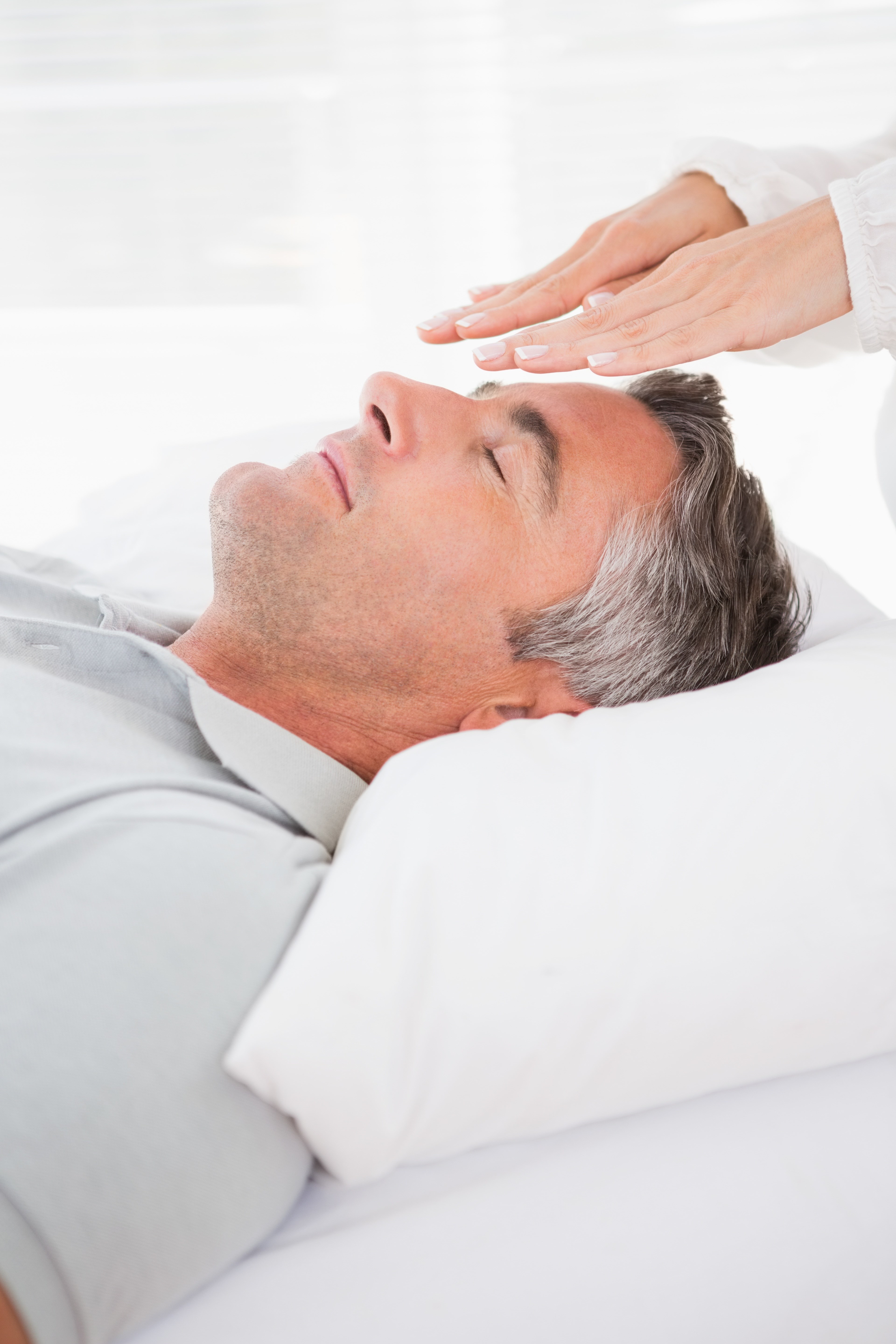 A man laying in bed with his hand on his head.