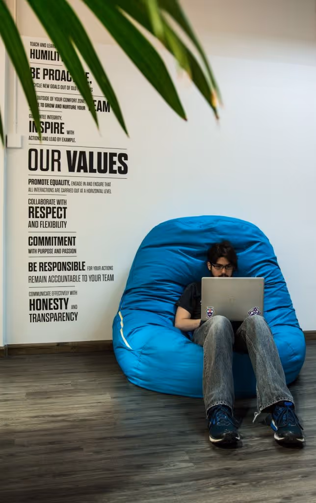 Photo of a software developer coding sitting on a puff couch