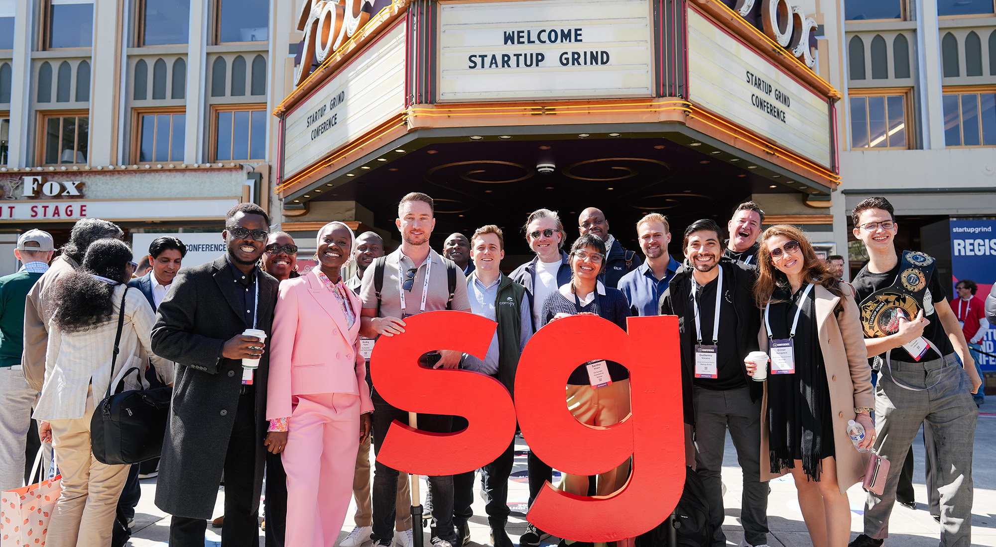 Diverse group of founders posing outside the Startup Grind Conference in Redwood City, highlighted as a must-attend 2026 tech event for global networking and community building.