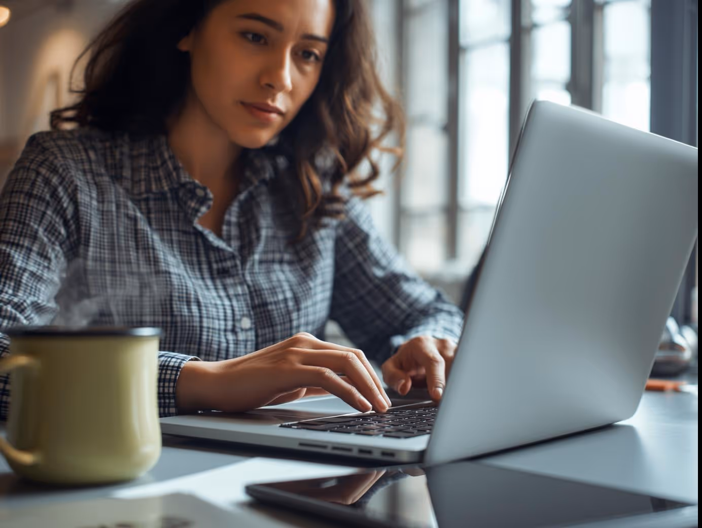 Email marketer typing subject lines for email campaign on laptop in workspace.