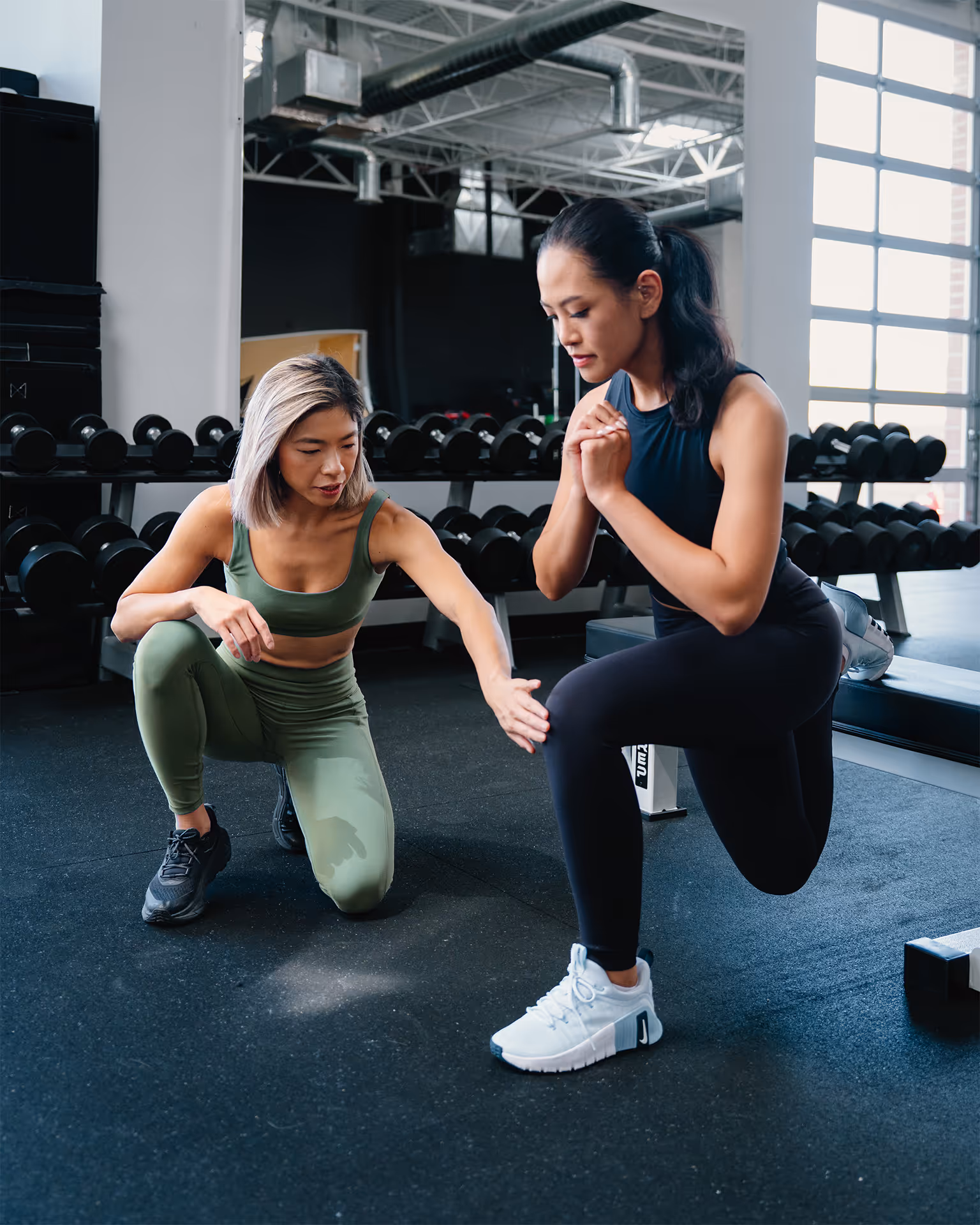 Aretha helping a female athlete do a Bulgarian split squat.