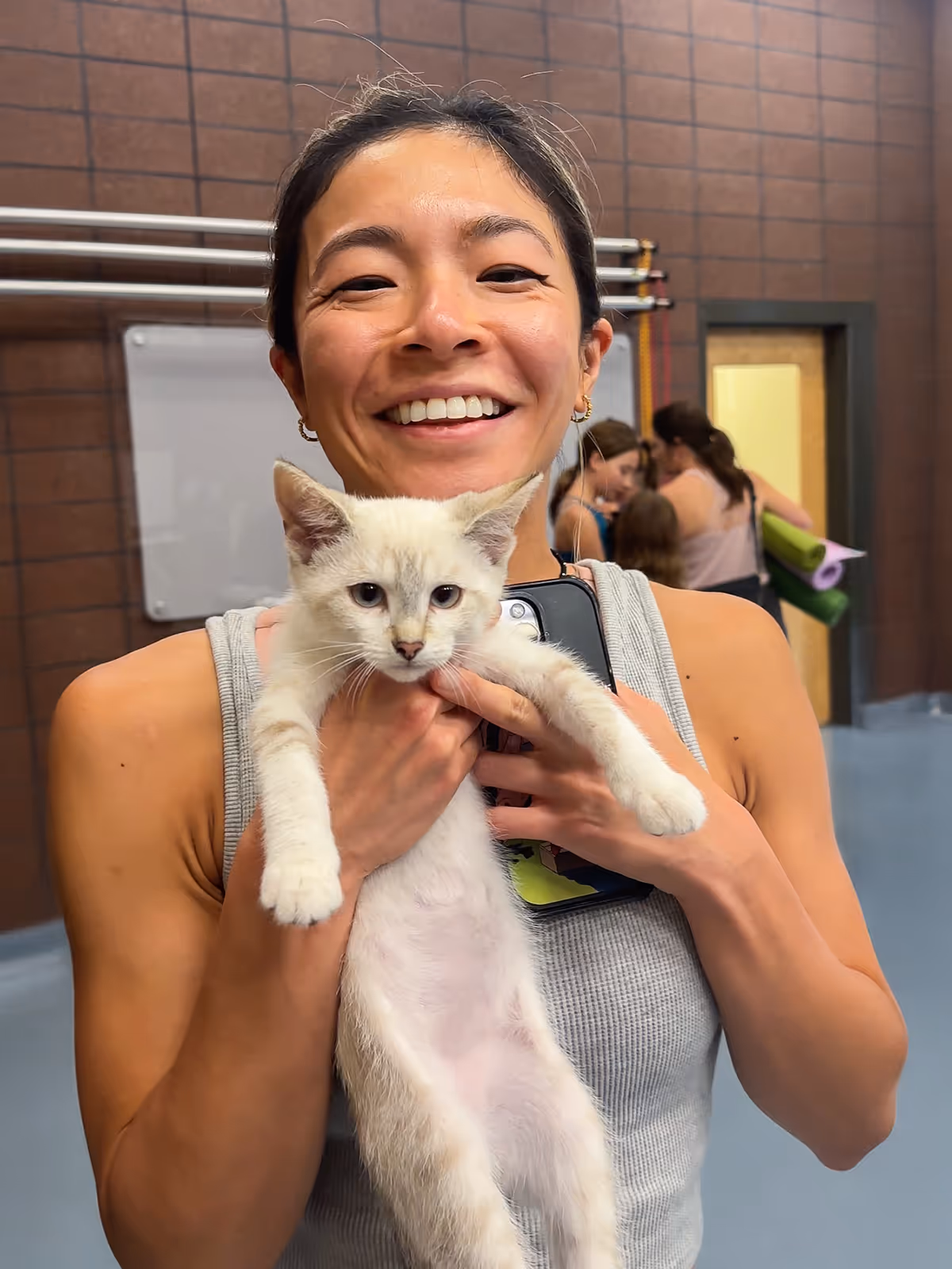 Aretha smiling holding a kitten.