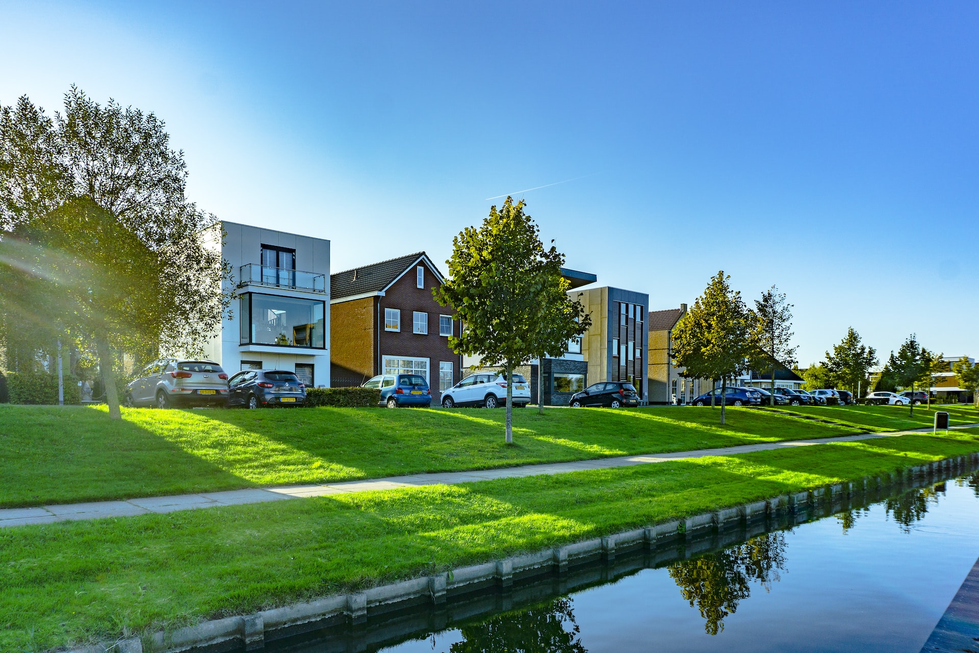 Weißes und braunes Haus am Fluss mit grüner Wiese